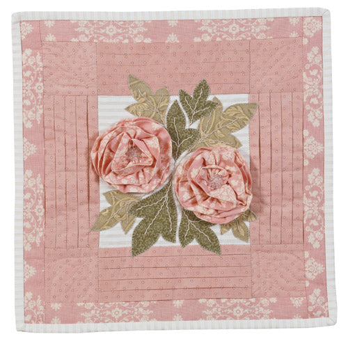 Flat shot of pink flower cushion with pleating, appliqué leaves and 3d fabric flowers