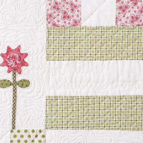 Closeup of appliqué flower and text quilting saying 'love little sausage dogs'