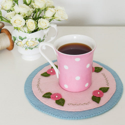 Styled shot of mug rug with flower embellishments with mug of tea