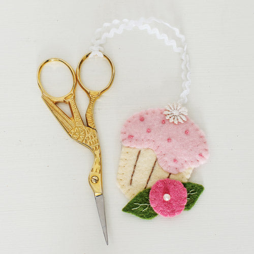 Closeup of cupcake shaped scissor fob attached to embroidery scissors