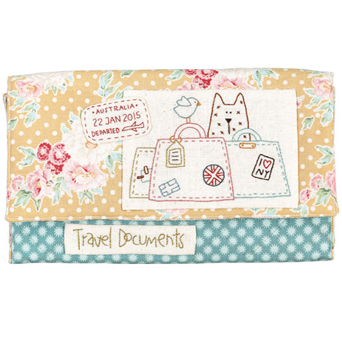 Flat shot of embroidered passport folio with cat, bird, luggage and departure stamp