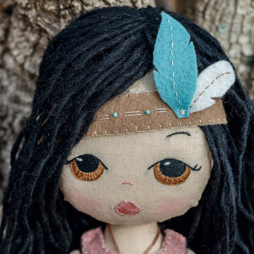 Closeup of Pocahontas doll's face wearing headband with feathers