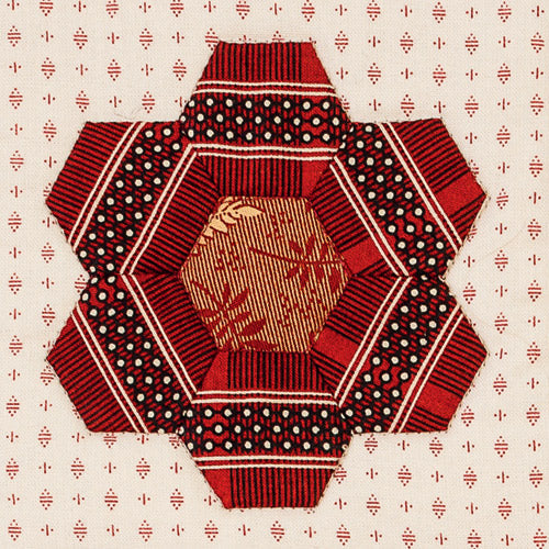 Closeup of fussy cut hexie flower from english paper pieced hexagon flower quilt