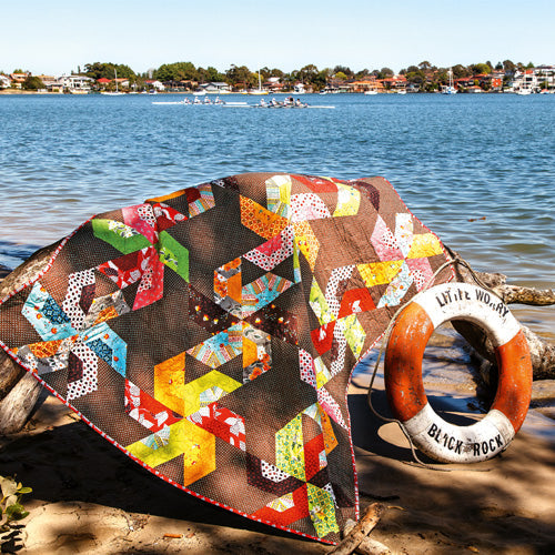 Styled shot of large pinwheel patchwork quilt by the water