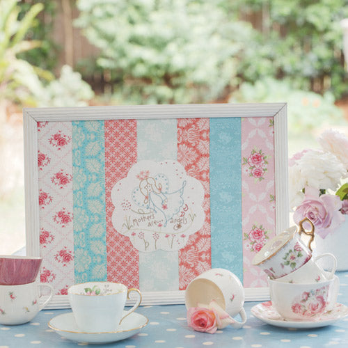 Styled shot of pretty framed angel embroidery with teacups and roses