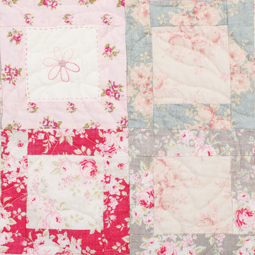 Closeup of four patchwork squares with embroidered flower from pretty embroidered patchwork quilt