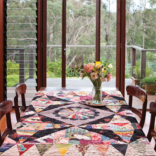 Styled shot of foundation pieced and appliqué asian string pieced quilt on table