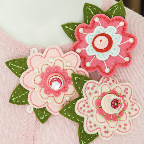 Styled shot of three felt and embroidery flower brooches pinned on cardigan