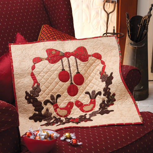 Styled shot of mini christmas appliqué wallhanging quilt on armchair