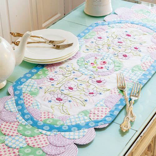 Styled shot of clamshells and embroidered flowers tablerunner on table