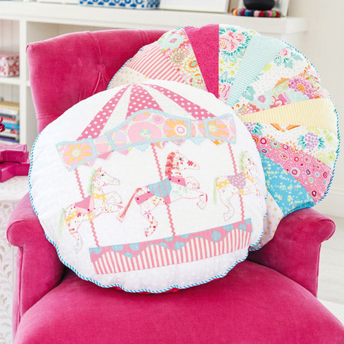 Styled shot of two round cushions, with appliqué horse carousel and patchwork sprocket