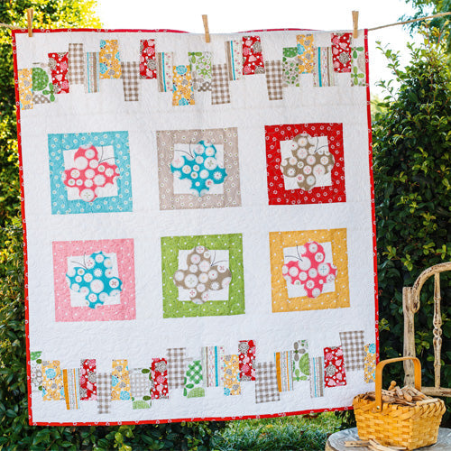Styled shot of appliqué and patchwork butterfly quilt hanging up in garden
