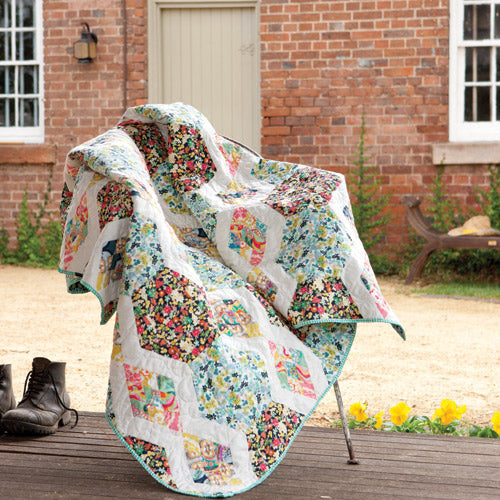 Styled shot of diamond and hexagon patchwork quilt draped on chair outside