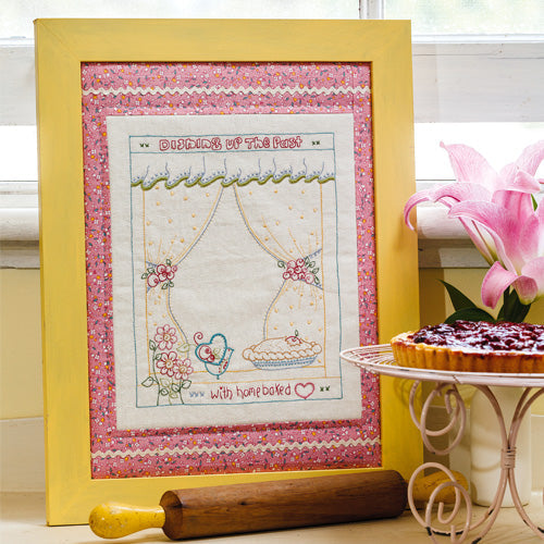 Styled shot of framed retro style embroidery with rolling pin and tart