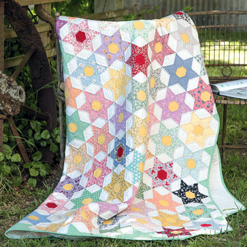 Scrappy English paper pieced star quilt styled on chain outside