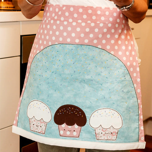 Styled shot of apron with embroidered sprinkle appliqué cupcakes being worn