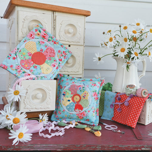 Styled shot of dresden plate pincushion and sewing book with flowers