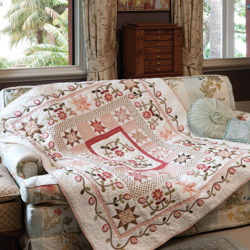 Styled shot of medallion antique style appliqué and patchwork quilt draped over couch