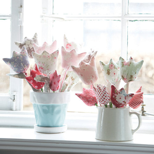 Styled shot of two bunches of fabric tulips in jug and pot