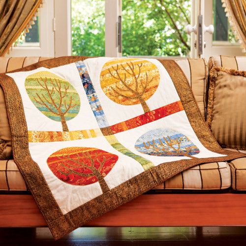 Styled shot of four seasons appliqué and embroidered trees on couch