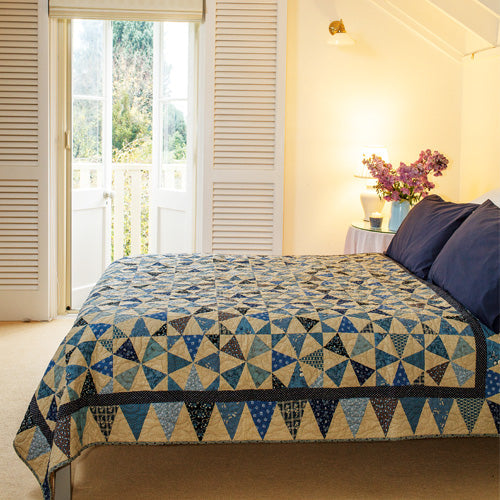 Styled shot of two colour kaleidscope patchwork quilt on bed