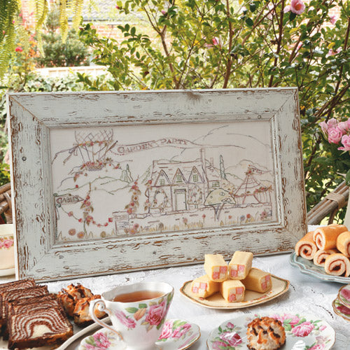 Styled shot of garden party framed embroidery on table with cakes