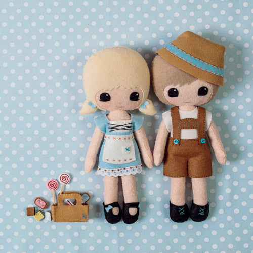 Styled flat shot of hansel and gretel dolls with basket of felt candy on blue and white spot background