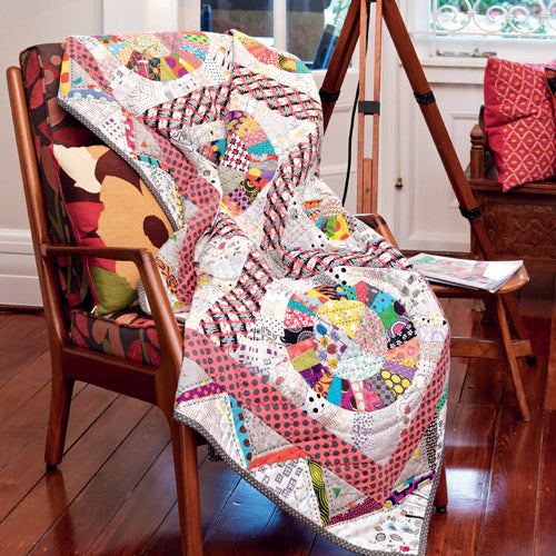 Scrappy, bright, modern circle quilt draped over chair