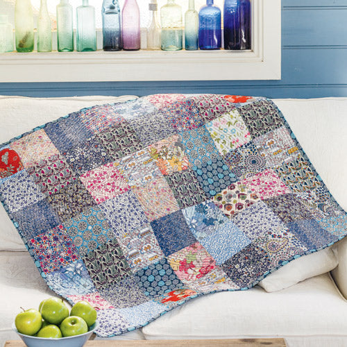 Styled shot of patchwork and heart appliqué quilt on couch