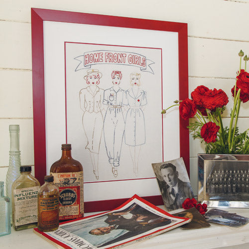 Styled shot of framed retro-style embroidery of wartime women with vintage bottles