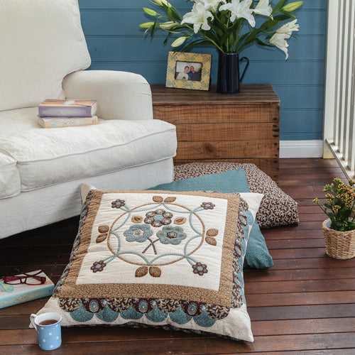 Styled shot of appliqué and english paper pieced traditional style cushion with cup of tea
