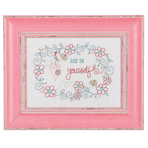 Flat shot of framed embroidery with flowers, hearts and bees around words 'just be yourself'