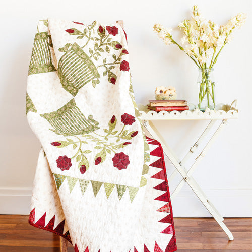 Styled shot of appliqué basket and flower quilt draped over chair