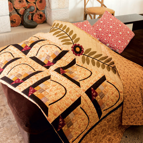 Styled shot of patchwork and appliqué basket quilt on couch