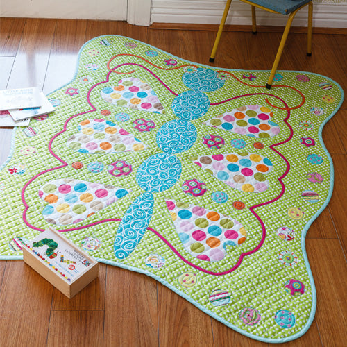 Styled shot of appliqué butterfly cot quilt on floor