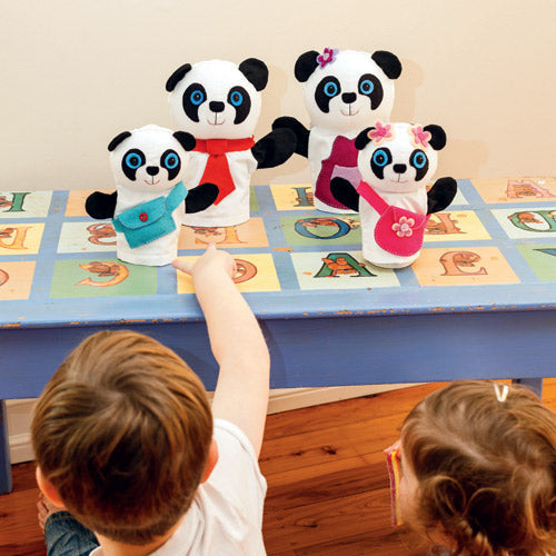Styled shot of two children playing with family of four panda puppets