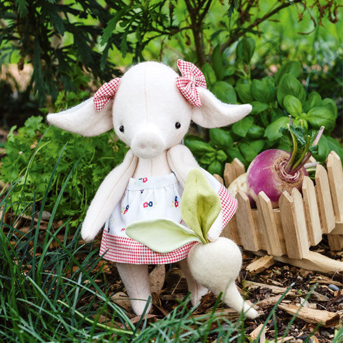 Styled shot of pig soft toy wearing skirt and bows with felt and real turnip outside in garden