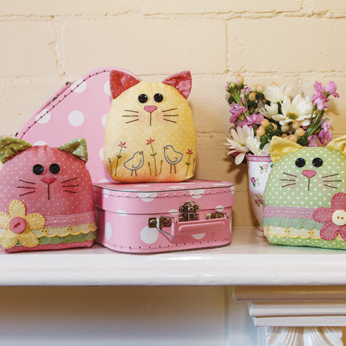 Styled shot of three appliqué and embroidered kitty softies