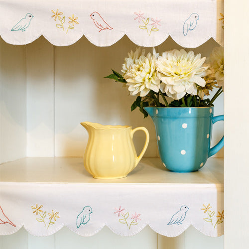 Styled shot of retro embroidered bird and flower shelf edging on shelves
