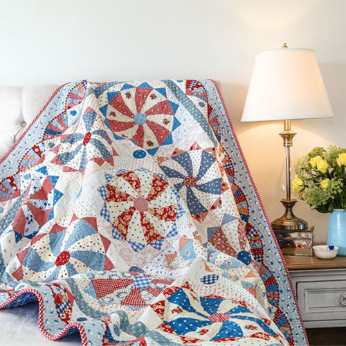 Styled shot of blue, white and red foundation pieced circle quilt with curved piecing and appliqué