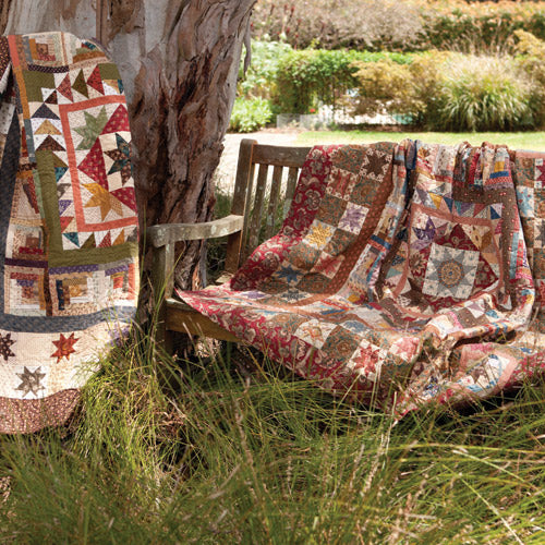 Styled shot of two versions of star medallion quilt outside under tree