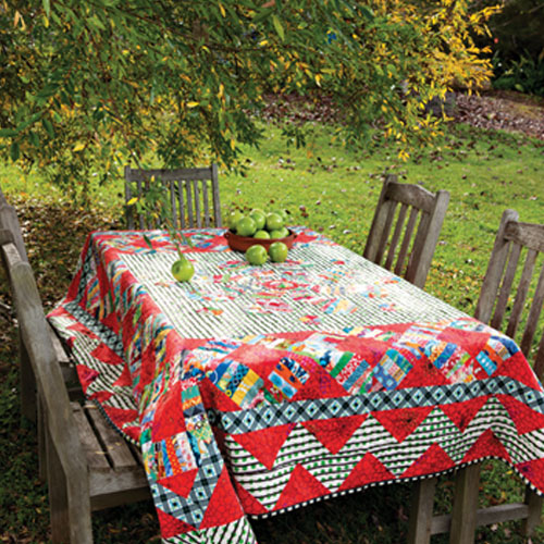 Styled shot of modern scrappy string pieced and appliqué quilt on outside table